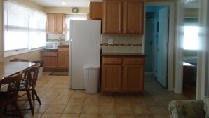 A kitchen with wooden cabinets, a white refrigerator, a microwave, and a dining area with chairs.