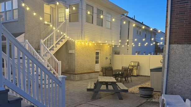 A residential building with a staircase, outdoor seating, and string lights.