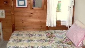 Una habitación de cabaña de madera con una cama, un espejo y un cuadro en la pared.
