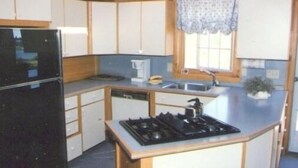 Cocina pequeña con estufa, pileta y alacenas.