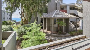 A courtyard with a gazebo, surrounded by greenery and a view of the sea. - Cumberland Resort Lorne private Apartment near beach, pool, spa, tennis, shops (Lorne)