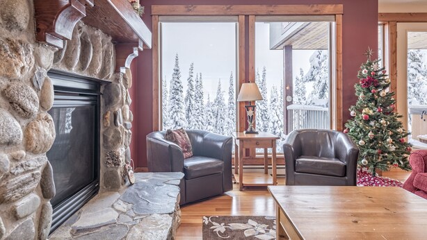 Una sala de estar acogedora con chimenea de piedra, sillones de cuero, una mesa de centro de madera y un árbol de Navidad.
