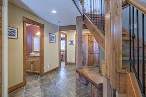 Stunning hallway with a central staircase, framed artwork, and dark stone flooring.