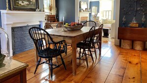 Un comedor con una mesa y sillas de madera, una chimenea y vista a otra habitación.