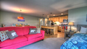 A compact living space with a red sofa, a bed, a kitchenette, and a dining area. - Sweet Suite! Modern, Pool, 2RM, 2BA, Ski Resort 532 (Killington)