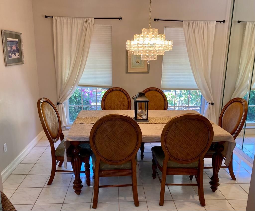 Comedor con una mesa dispuesta para seis personas, rodeada de sillas de madera con asientos acolchados.