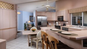 A modern kitchen with a central island, stainless steel appliances, and light wood cabinetry. - Avail August 28 & on. Sunny New heated Pool & Spa 10min walk2beach 6-bikes (Marco Island)
