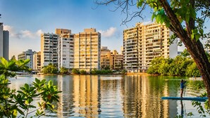 A calm lake with a paddleboarder, surrounded by modern high-rise buildings. - Condado Lagoon View - Apartment at Miramar: Beach, Night Life, family and more!! (San Juan)
