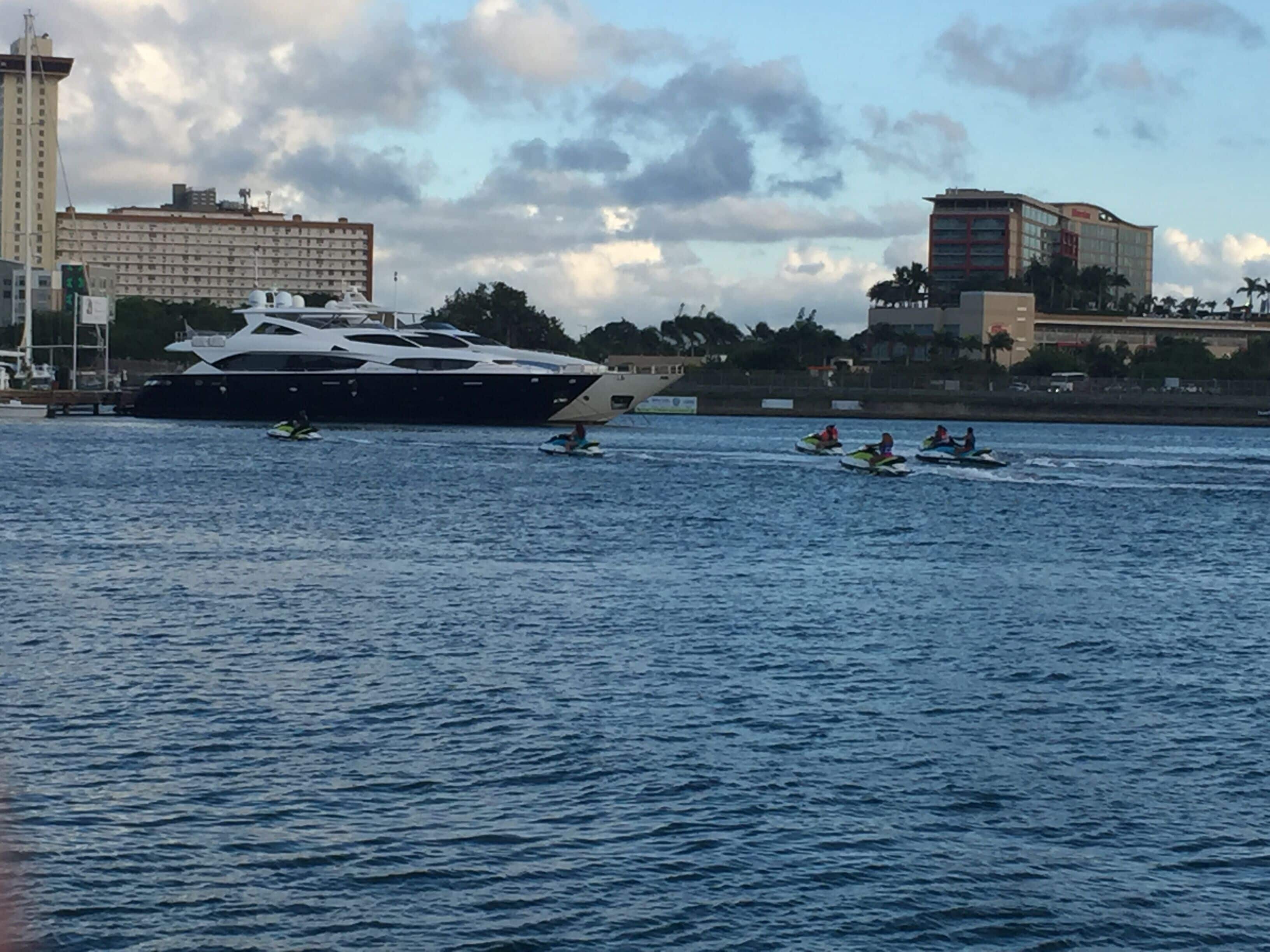 Un grand yacht était amarré près d’une marina, et plusieurs bateaux à moteur étaient sur l’eau.