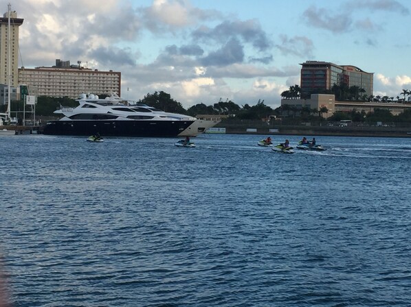 A large yacht docked near a marina with several speedboats in the water.