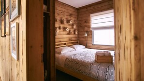 Ein Zimmer mit Holzboden, einem Bett, einem Fenster und an den Wänden befestigten Vogelhäusern.