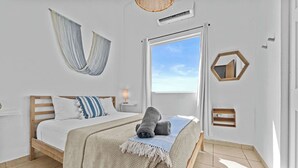 Une chambre avec un grand lit, un hamac, une fenêtre donnant sur un beau paysage et un miroir hexagonal.