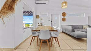 Un salon moderne avec un canapé gris, une table à manger en bois avec des chaises et une grande fenêtre donnant sur un beau paysage.