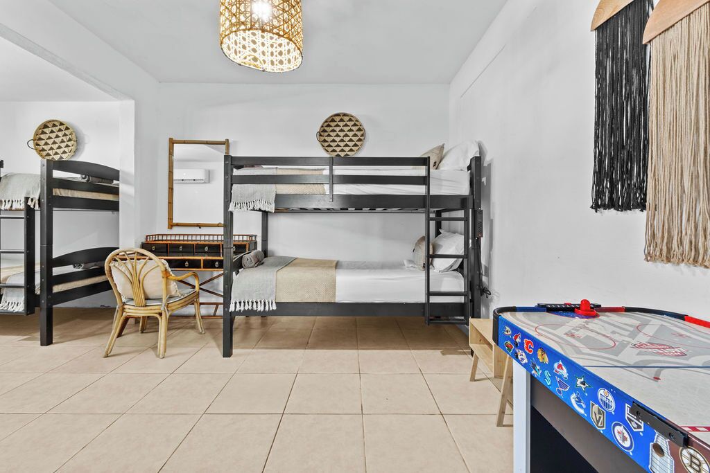 A dormitory room with bunk beds, a desk, a chair, and a table with a hockey puck.