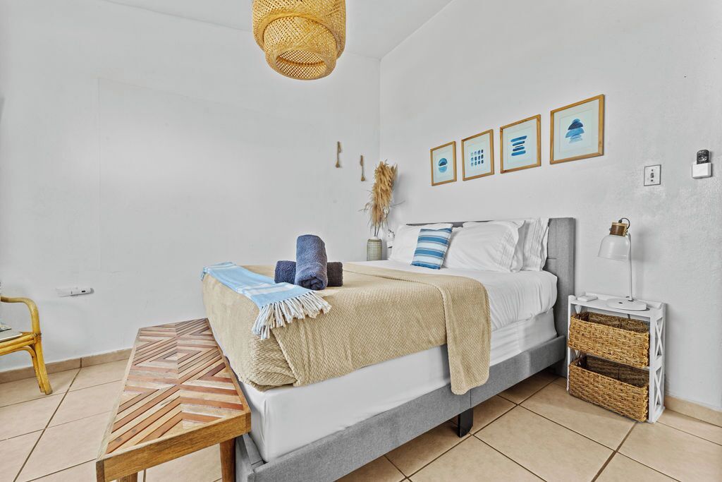 A bedroom with a bed, bedside table, lamp, and wall art.