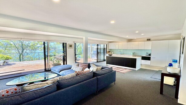 Ein modernes Wohnzimmer mit einem großen Sofa, einem Glastisch und Blick ins Freie.