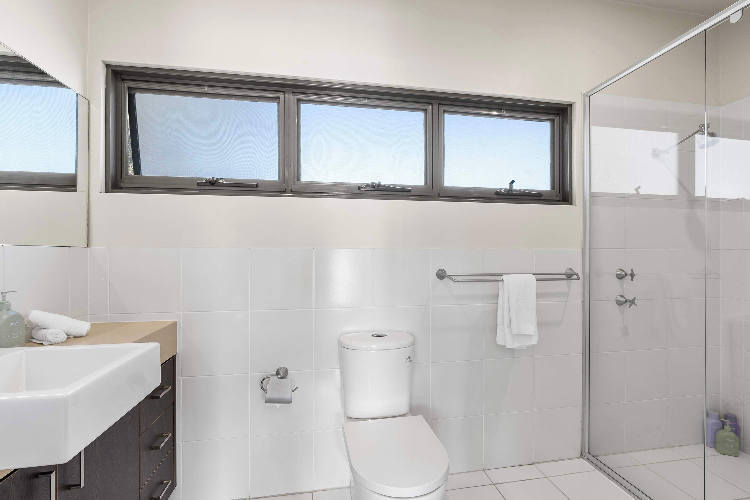 A modern bathroom with a toilet, sink, and shower.