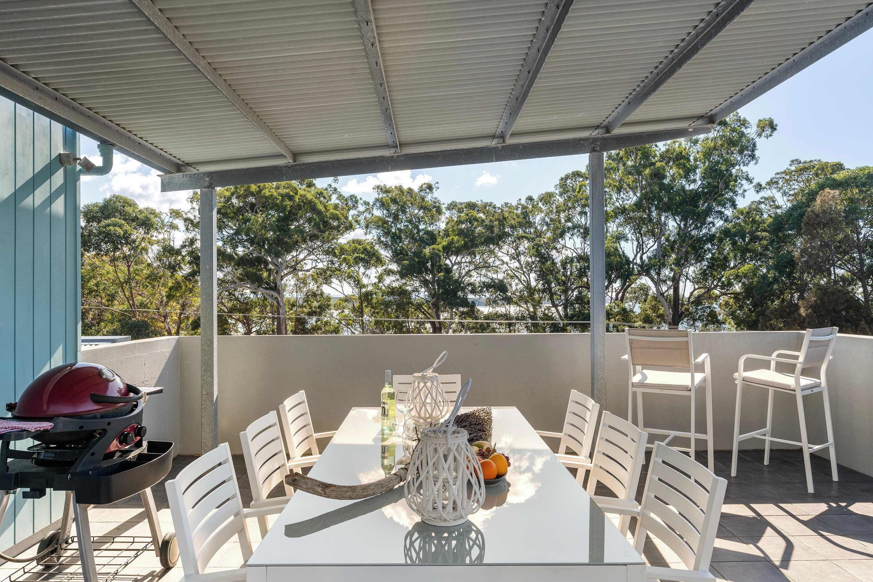 An outdoor patio with a table, chairs, a grill, and a decorative lantern.