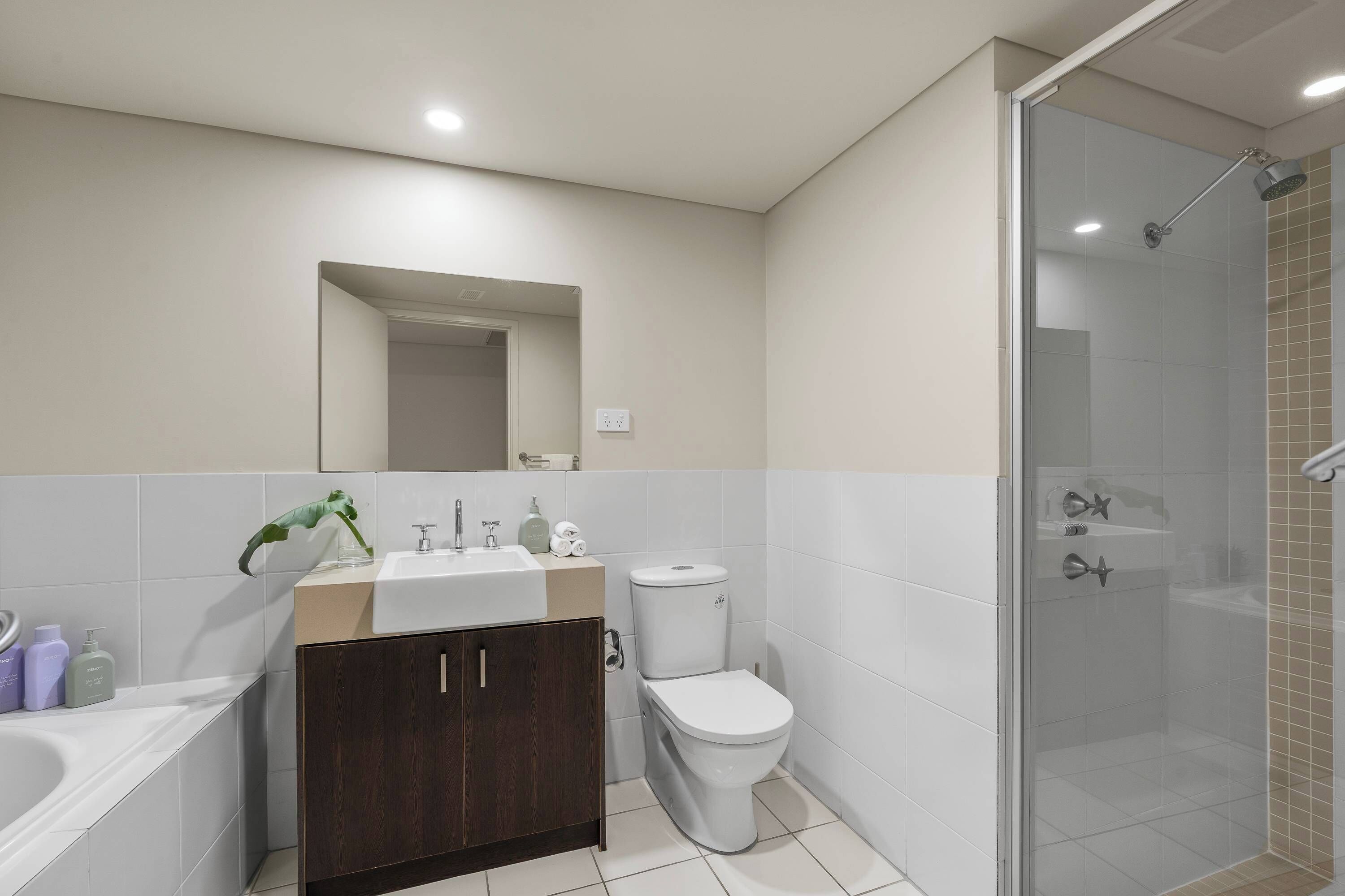 A modern bathroom with a shower, toilet, sink, and cabinet.