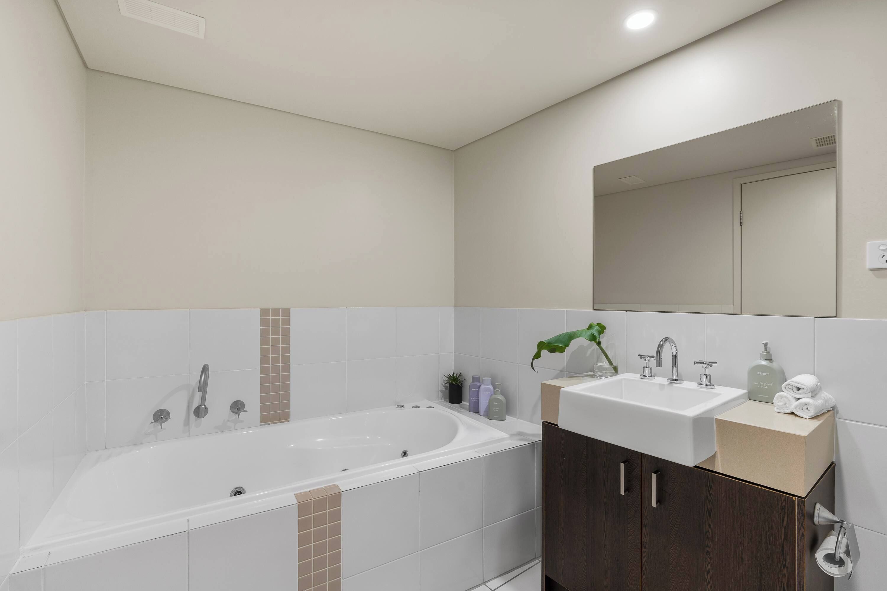 A modern bathroom with a bathtub, a sink, and a mirror.