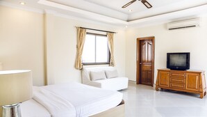 A bedroom with a bed, a sofa, a TV, and a wooden cabinet. - 8bdr Avoca Pool Villas 172 (Muang Pattaya)