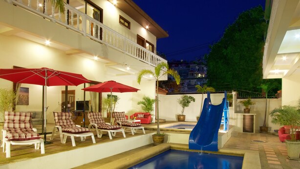 A swimming pool with lounge chairs and umbrellas, a slide, and a balcony with plants. - 8bdr Avoca Pool Villas 172 (Muang Pattaya)