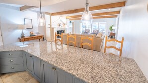A kitchen with granite countertops, wooden chairs, and pendant lighting. - Packsaddle Paradise- Lakefront w/ Beach & Views (Kingsland)