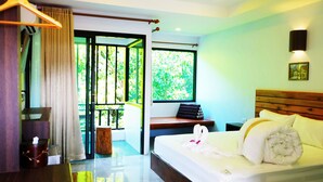 Une chambre d’hôtel avec un lit, un banc près de la fenêtre et une vue sur la verdure.