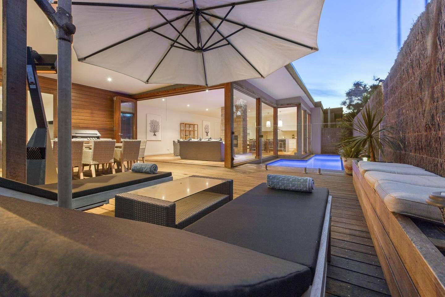 An outdoor patio with lounge chairs, a dining area, and a swimming pool.