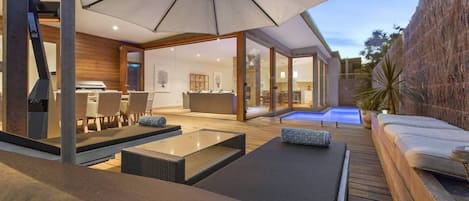 Un patio al aire libre con sillones, una zona de comedor y una piscina.