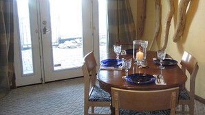 Un coin repas avec une table dressée pour quatre personnes, agrémenté d’une bougie, de verres et d’assiettes.