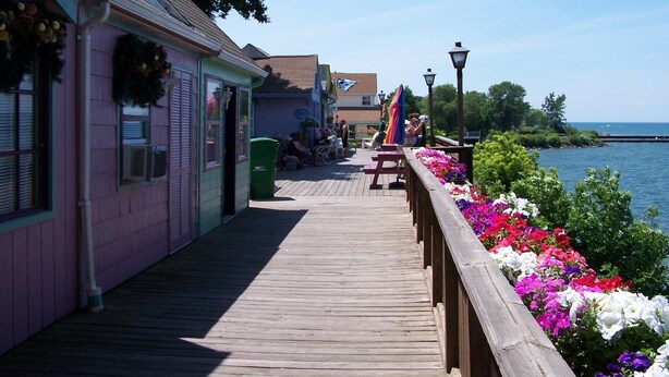 Une jetée en bois, bordée d’un côté par une rangée de fleurs aux couleurs vives et de l’autre par une rangée de maisons.