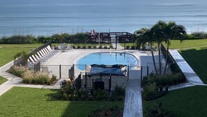 A pool area with a view of the ocean, surrounded by a deck and lounge chairs. - Oceanfront Condo With Incredible Views (Vero Beach)