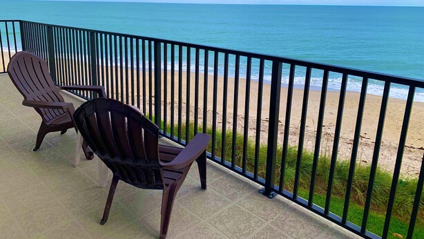 A balcony with two Adirondack chairs overlooking a beach. - Oceanfront Condo With Incredible Views (Vero Beach)