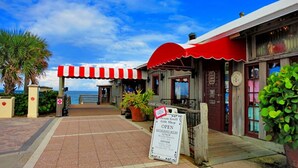 A beachfront restaurant with a red and white awning, a signboard advertising a gift shop, and a view of the ocean. - Oceanfront Condo With Incredible Views (Vero Beach)