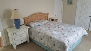 A bedroom with a wooden bed frame, a nightstand with a lamp, and a small bedside table.