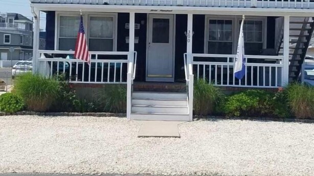 A two-story building with a balcony, a flag, and a staircase leading to the entrance.