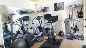 Una palestra in casa con attrezzature per l'allenamento, tra cui tapis roulant, ellittica, cyclette e pesi.