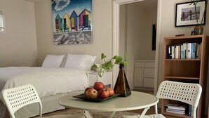 Una camera da letto con un letto, un comodino con una pianta, un tavolino rotondo con delle mele e una libreria.