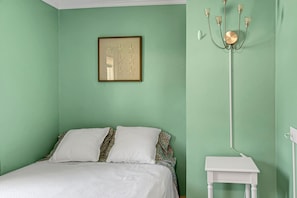 Una habitación con cama, una obra de arte enmarco y una lámpara de pie.