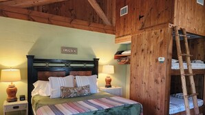 A wooden bedroom with a bed, two bedside lamps, a ladder, and a shelf with folded blankets. - Private, Cozy Cabin on 6 acres with Mountain Views in the Heart of the Texas Hill Country Near Lost Maples and Garner State Parks (Vanderpool)