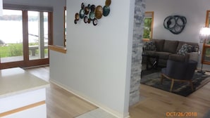 Una sala de estar moderna con un amplio ventanal, una pared de acento de piedra y una zona de estar con sofá y sillones.