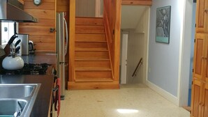 A wooden interior with a kitchen area, a staircase, and a hallway leading to another room. - Remarkable Four Gable House Overlooking Friendship Harbor (Friendship)
