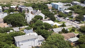 Vista aérea de una zona residencial costera con casas, una playa y una carretera.