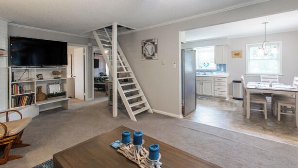 Un salón amplio con escalera, cocina y comedor.