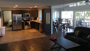 A modern kitchen with dark wood cabinets, stainless steel appliances, and a dining area with a wooden table and chairs. - Large Lake House 30 Feet From The Water With Private Dock Out The Door.  (Mears)