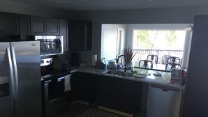 A modern kitchen with stainless steel appliances, a dishwasher, and a window providing natural light. - Large Lake House 30 Feet From The Water With Private Dock Out The Door.  (Mears)
