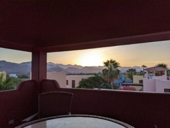Un balcon avec vue sur les montagnes et sur le coucher du soleil.
