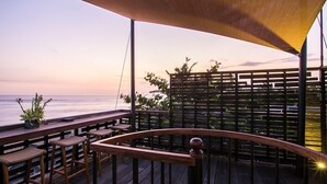 A wooden deck with a railing, overlooking a body of water. - 5 Bedroom villa Beachfront with private Pool in Canggu (Canggu)