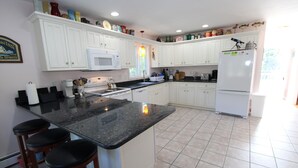 Eine Küche mit weißen Schränken, einer schwarzen Granit-Arbeitsplatte und einem weißen Kühlschrank.